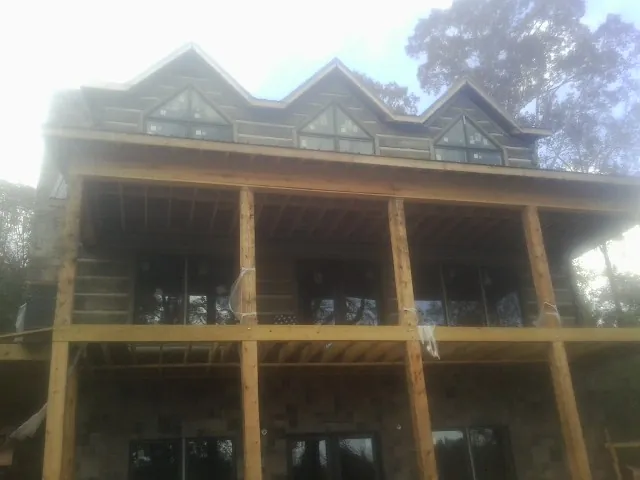 Dormers and porch framing on a large log home under construction — Roof Coating work by our crew in Anahuac