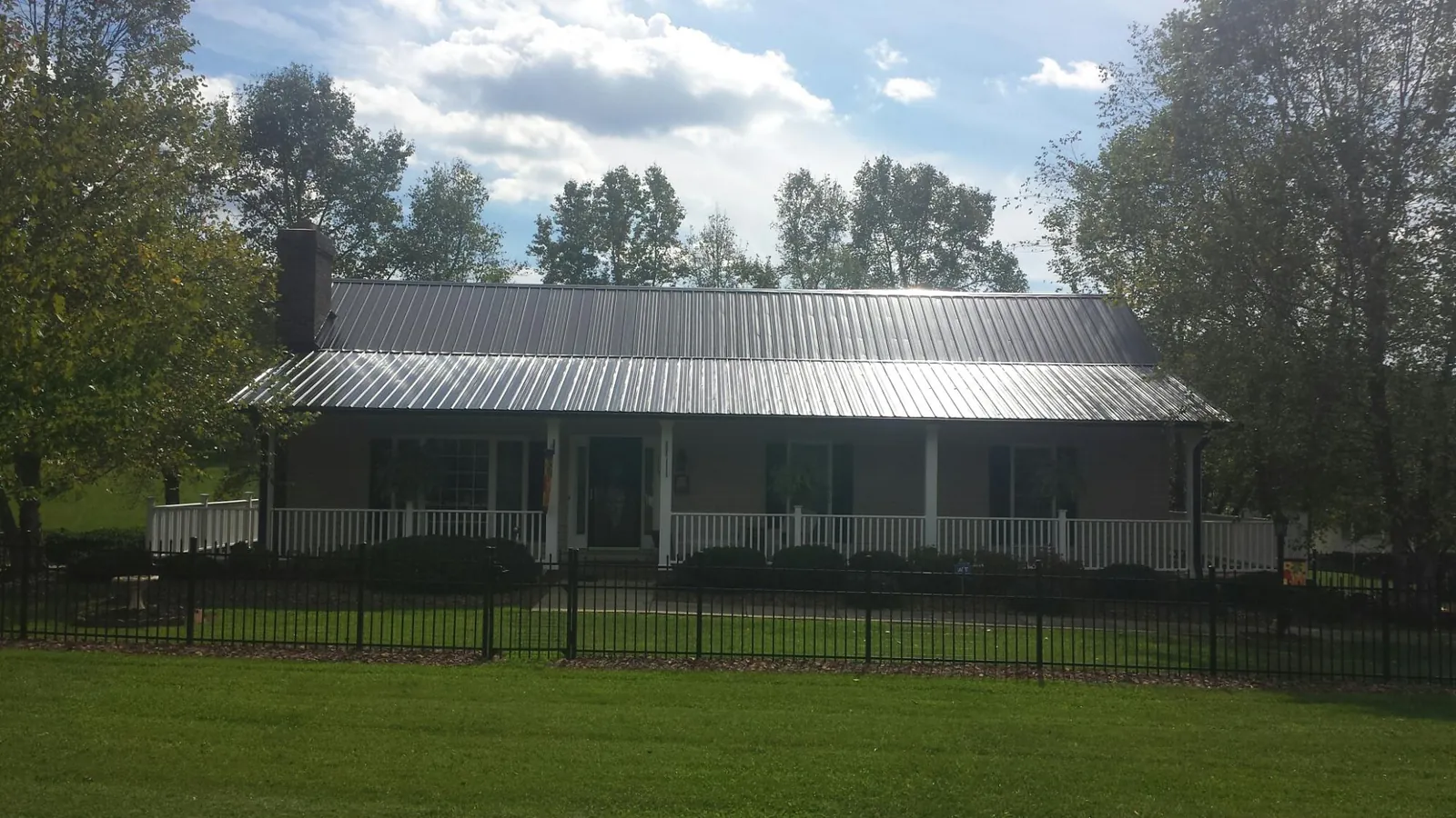 Gray metal roof on a brick ranch with a full width front porch — Gutter Guard Installation work by our crew in Anahuac