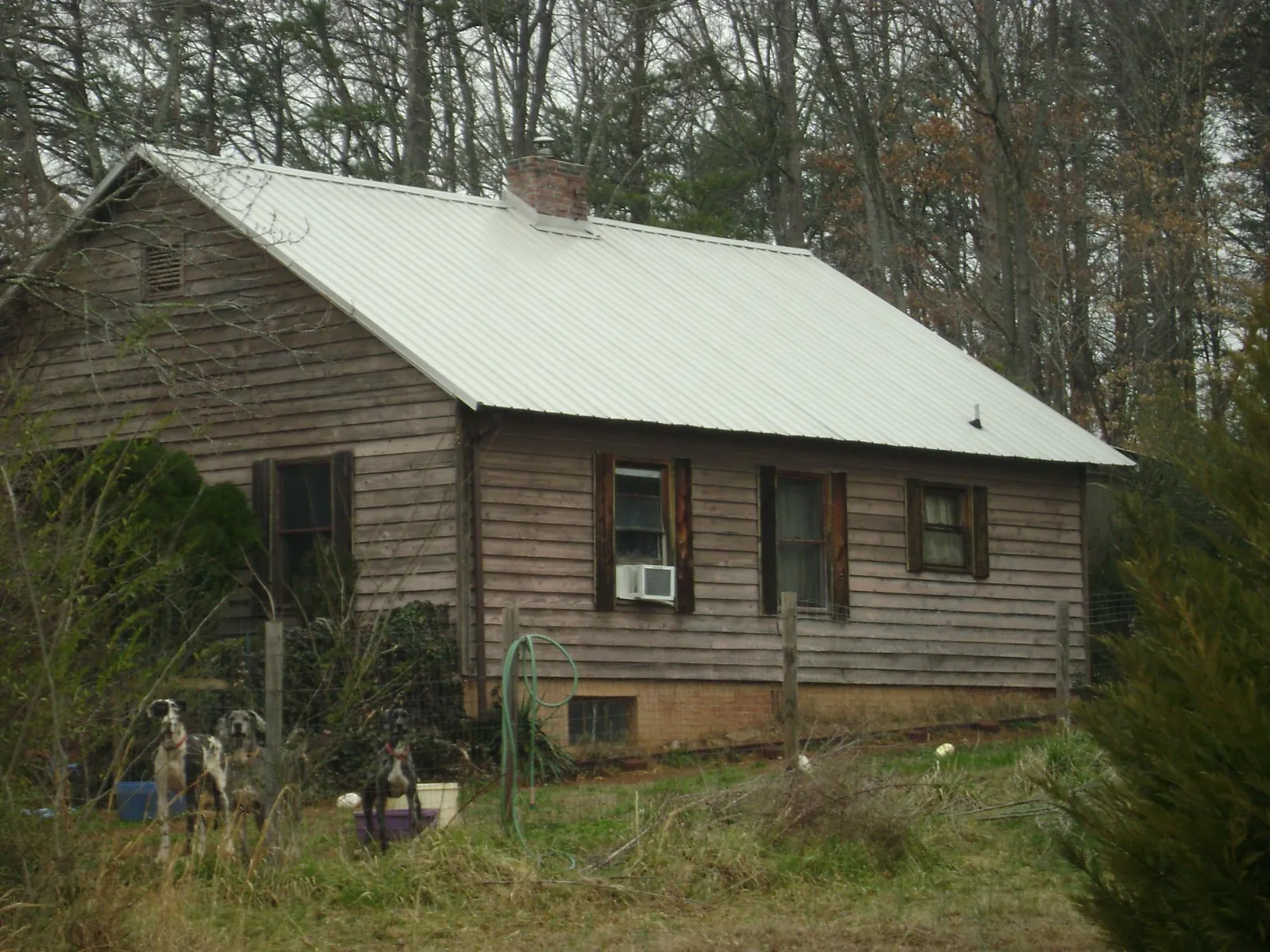 White metal roof on an old wood sided farmhouse, from a Metal Roof Installation job in Anahuac