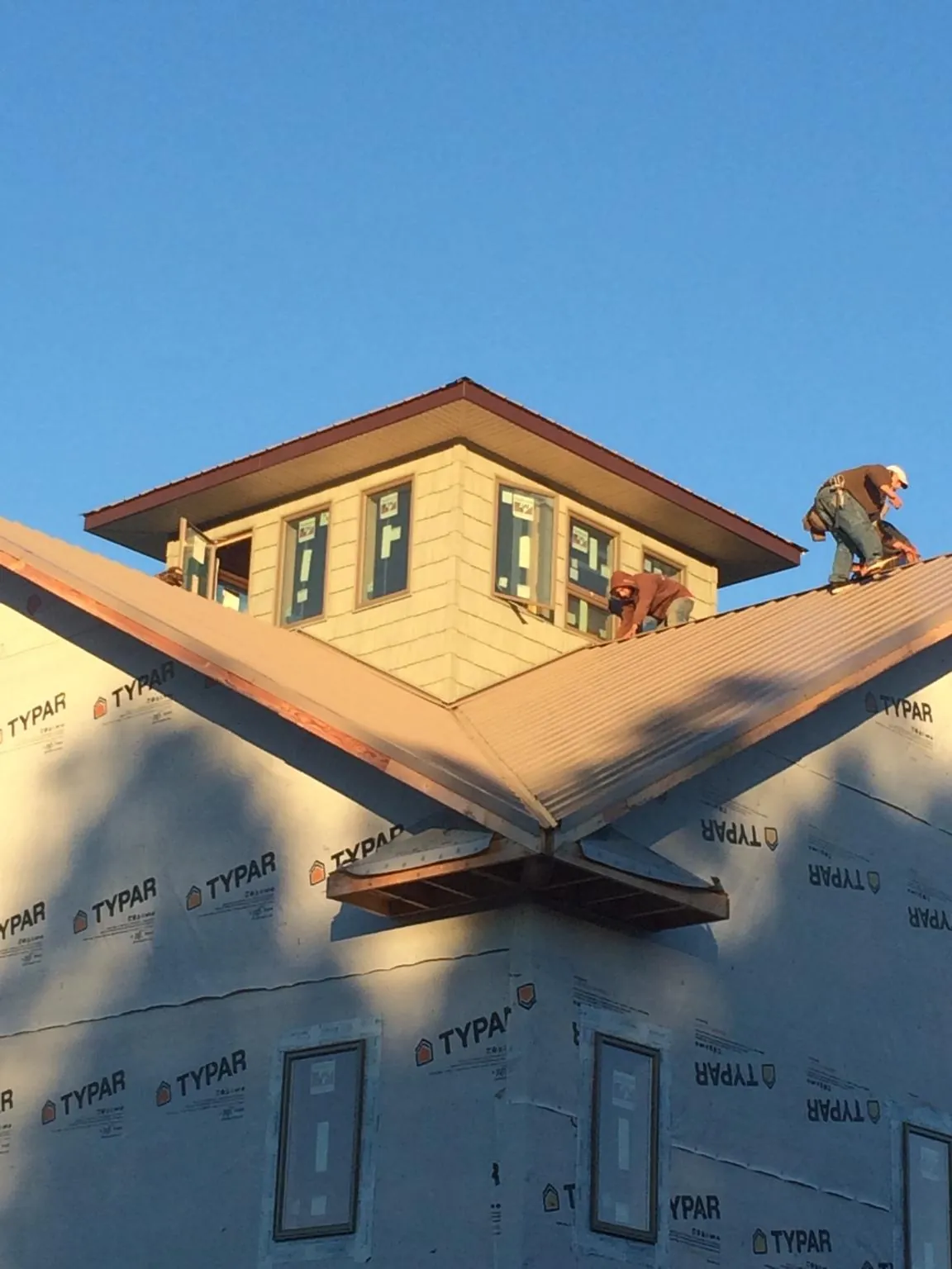 Roofers working around a rooftop cupola on a new metal roof at sunset — Roof Waterproofing in Anahuac by Roofing Brothers